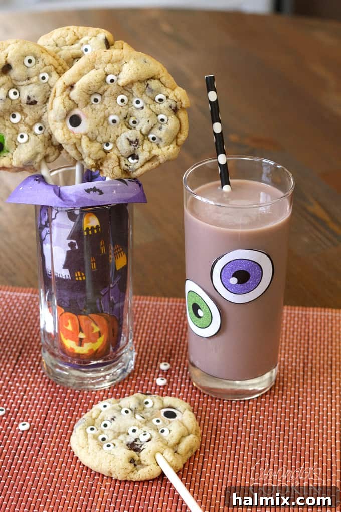 Monster Eyeball Cookie Pops served with milk. A fun Halloween treat for all ages! #halloweencookies #monstercookies #eyeballcookies #chocolatechipcookies #halloweenrecipes #candyeyeballs #lollipops #cookiepop Monster Cookie Pops served with milk