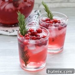 two glasses of cranberry holiday punch garnished with cranberries and rosemary