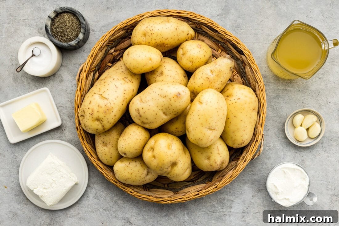 Easy Creamy Slow Cooker Mashed Potatoes 4 Ingredients for Crockpot Mashed Potatoes laid out on a countertop, including potatoes, broth, garlic, sour cream, cream cheese, and butter.