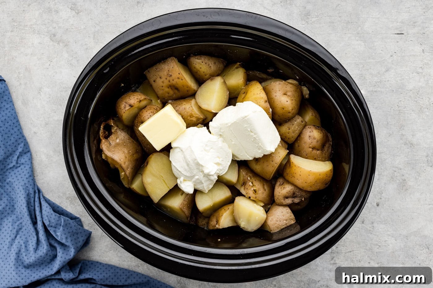 Easy Creamy Slow Cooker Mashed Potatoes 7 Sour cream, cream cheese, and butter placed on top of cooked, undrained potatoes in a crockpot, ready for mashing.