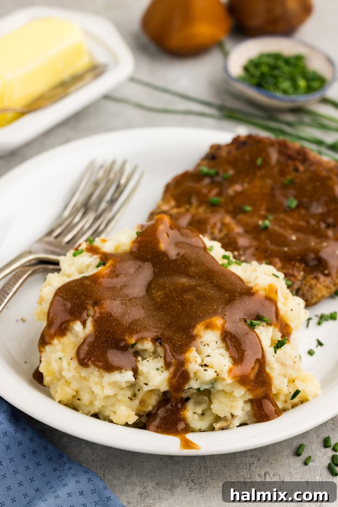 Easy Creamy Slow Cooker Mashed Potatoes 9 Crockpot Mashed Potatoes served on a white plate and generously topped with brown gravy, ready to eat.