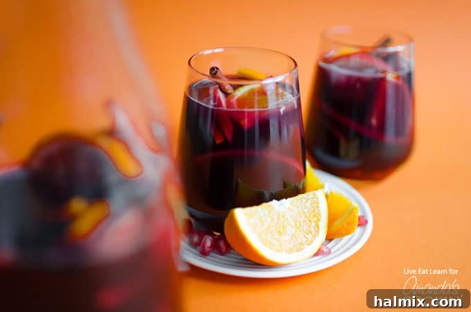 Delicious Pomegranate Sangria - Great for Fall or Thanksgiving! A refreshing glass of Pomegranate Sangria with an orange slice, perfect for fall or Thanksgiving celebrations.