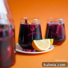 Pomegranate sangria with an orange wedge, a beautiful and delicious holiday drink.