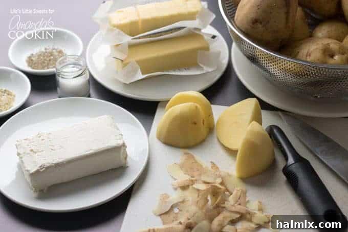 Velvety Mashed Potatoes 3 A selection of fresh ingredients laid out for making mashed potatoes: potatoes, butter, cream cheese, and seasonings.
