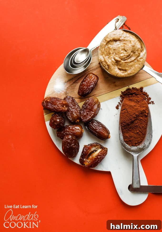A rustic board displaying the wholesome ingredients for chocolate freezer fudge: medjool dates, almond butter, cocoa powder, and coconut oil.