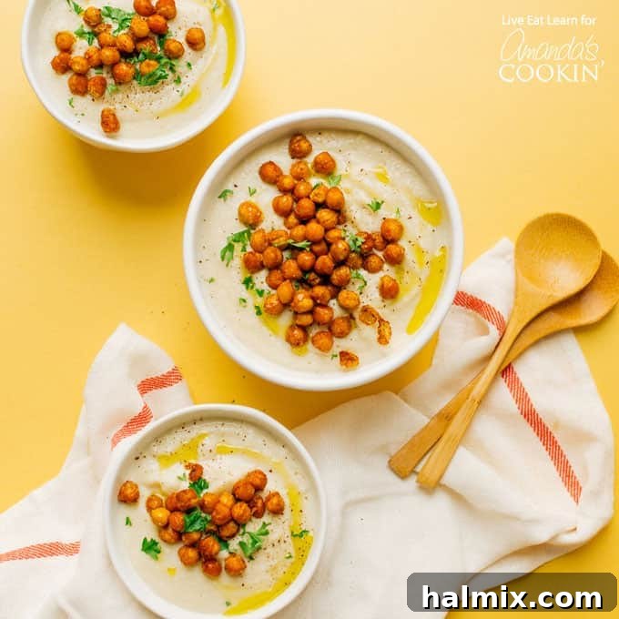 three bowls of cauliflower soup with chickpea garnish