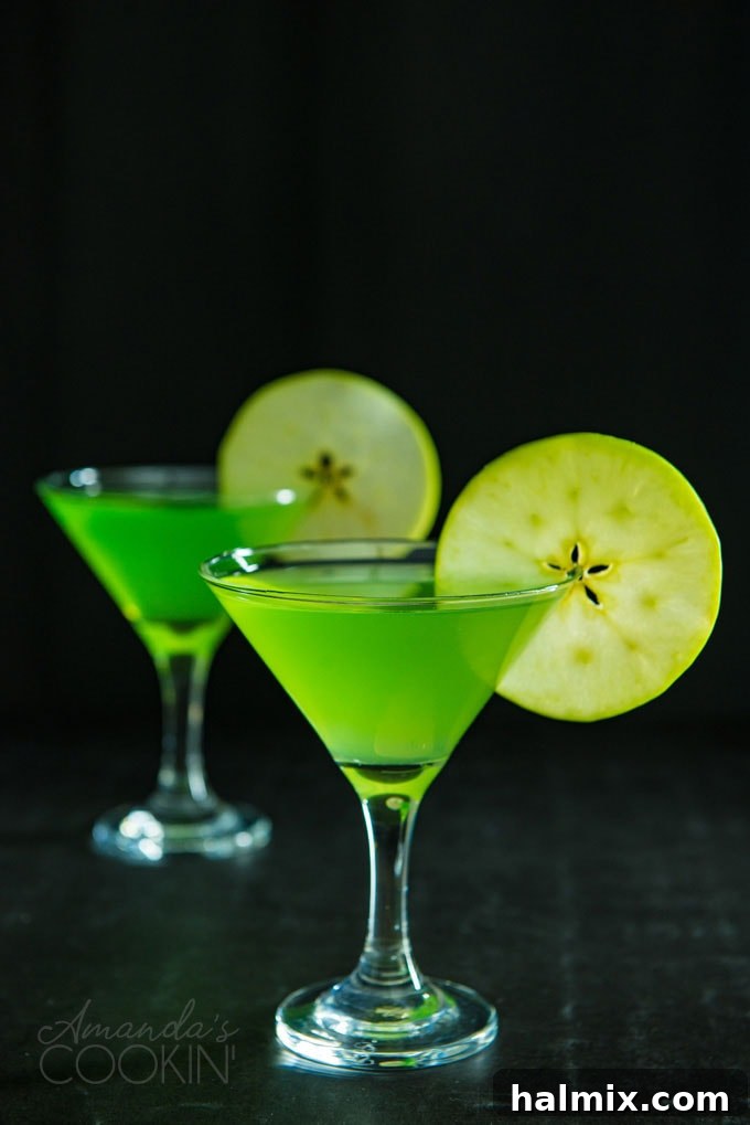 The Iconic Appletini Cocktail Two Appletini martinis on a dark background garnished with apple wheels, highlighting their vibrant color.