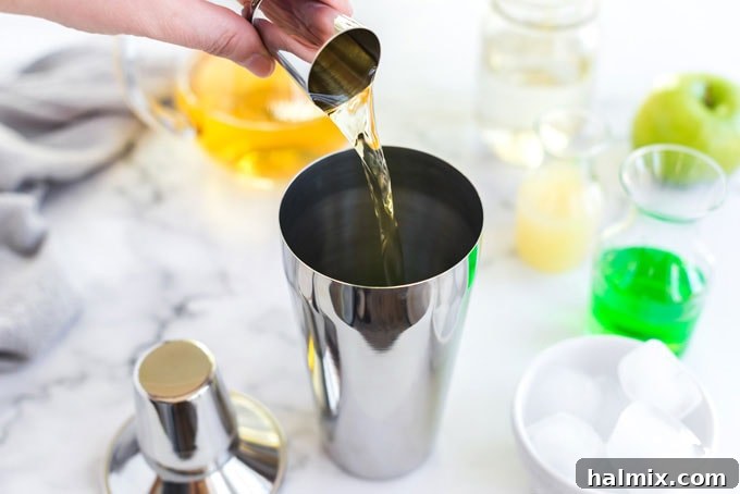 Apple Elixir 4 Adding a generous pour of fresh apple juice into the cocktail shaker, enhancing the fruity core of the Appletini.