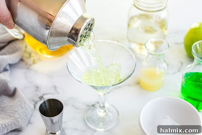 Apple Elixir 6 The perfectly chilled and mixed Appletini is expertly strained from the shaker into a elegant martini glass, ready for garnish.