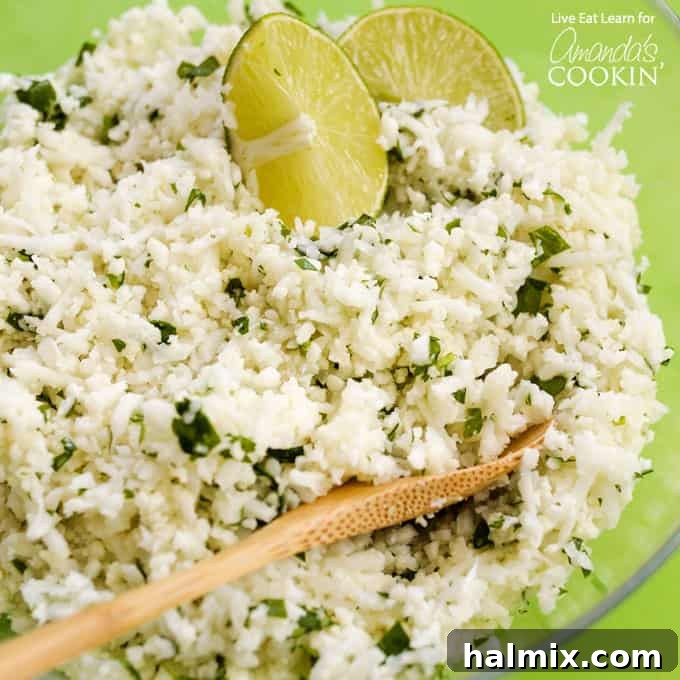 A serving bowl filled with fluffy cauliflower chipotle rice, garnished with a wooden spoon