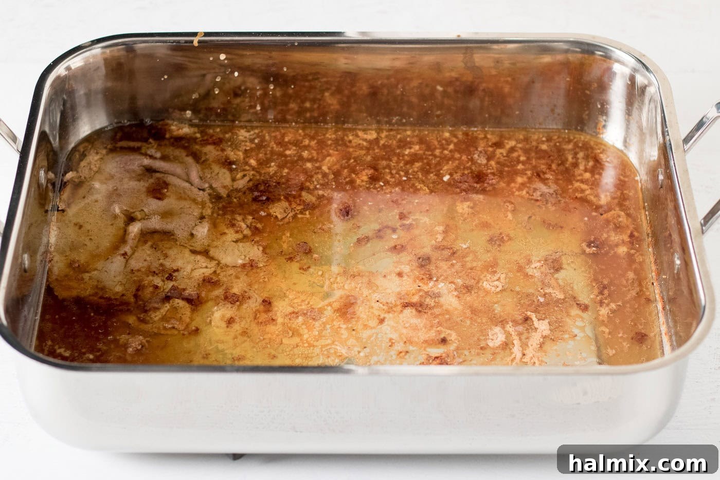 Roasting pan full of turkey drippings from roasting a turkey