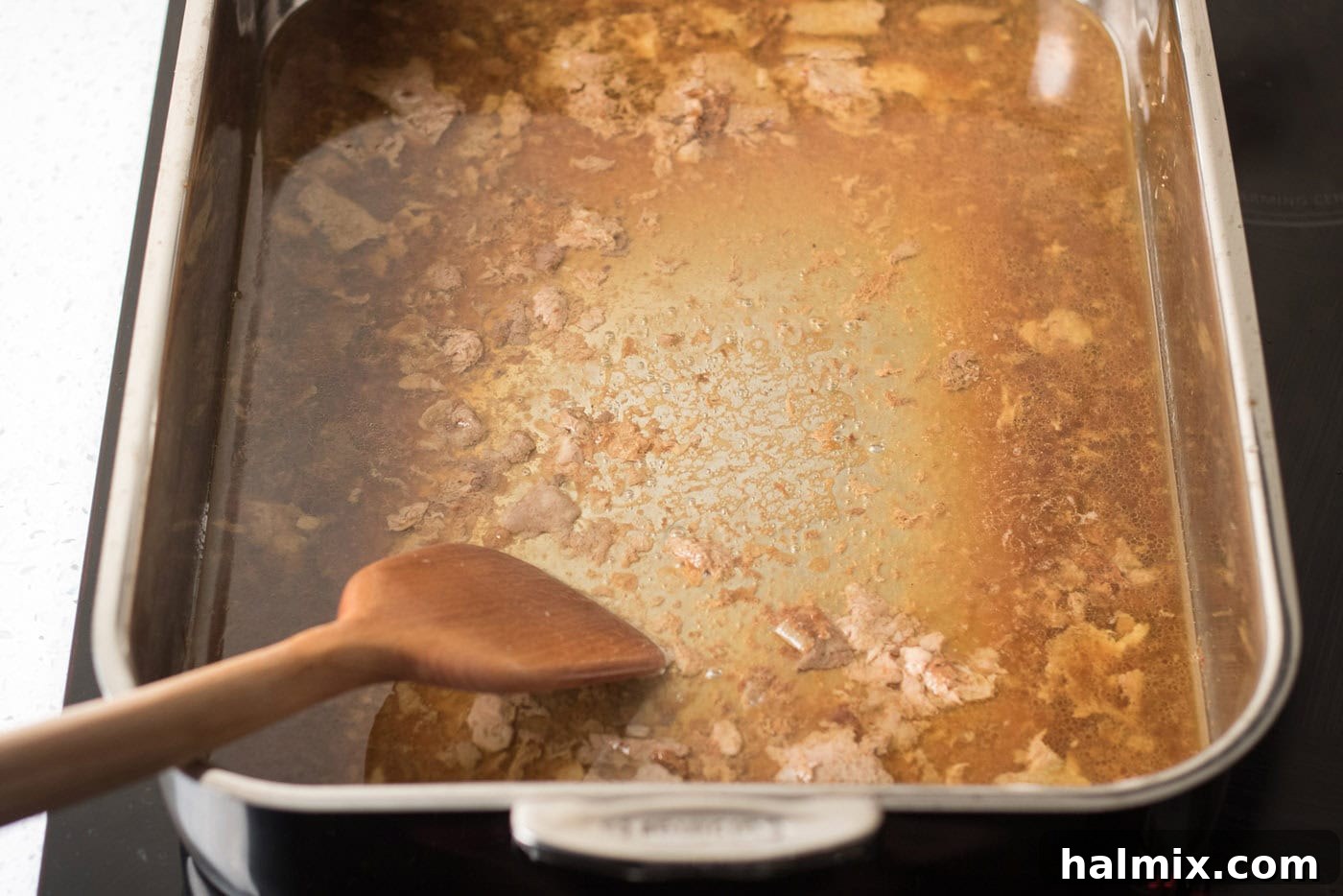 Spatula in a roasting pan full of pan drippings