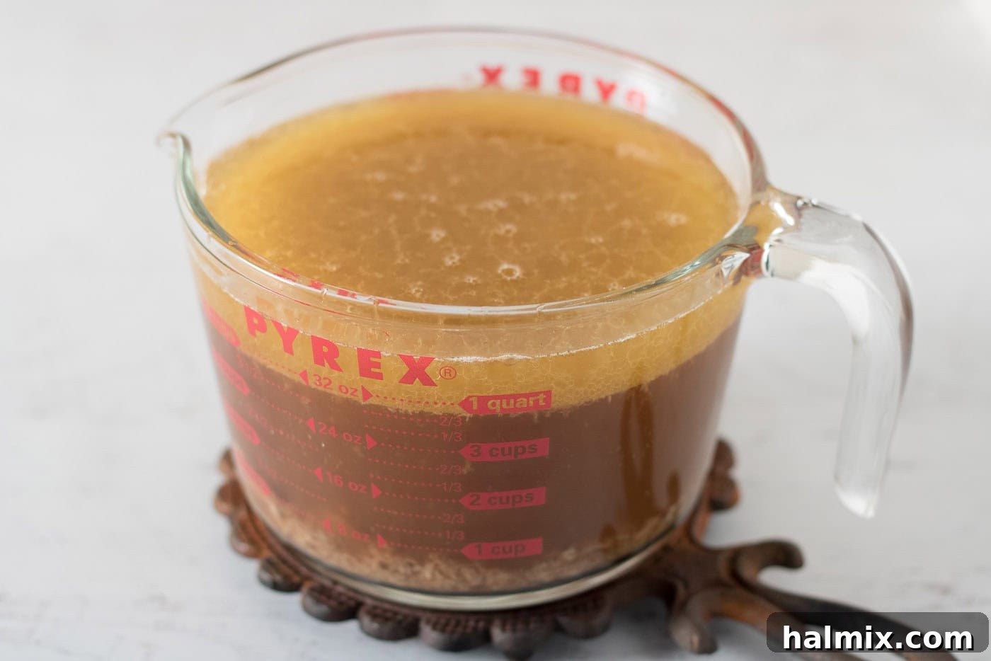 Wet measuring cup of broth and roasted turkey drippings
