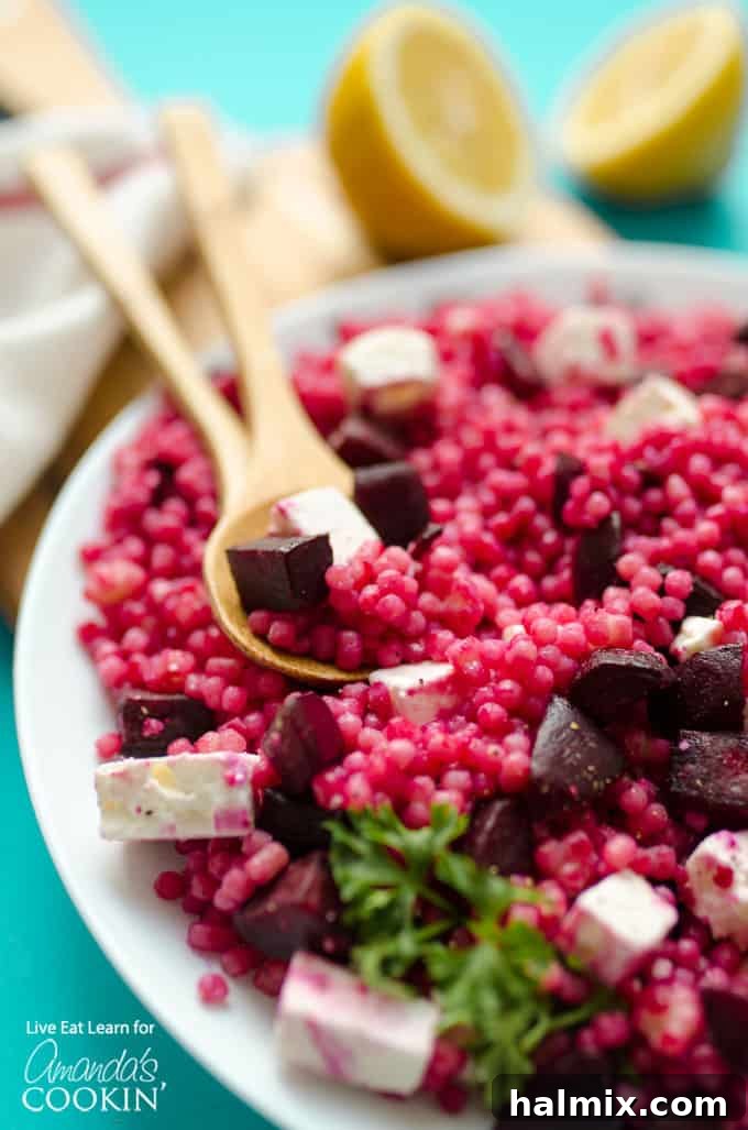 Vibrant Pearl Couscous Salad with Feta and Beet served in a white bowl, garnished with fresh herbs, showcasing its appealing colors and textures.