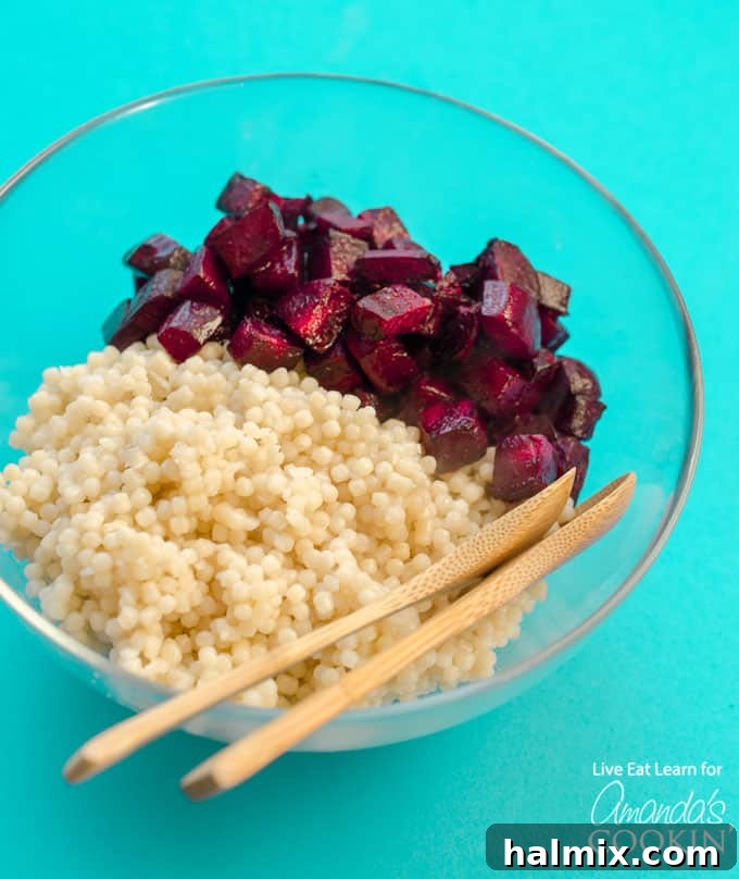 Cooked pearl couscous infused with the vibrant pink juice of roasted beets, waiting to be combined with feta and lemon.