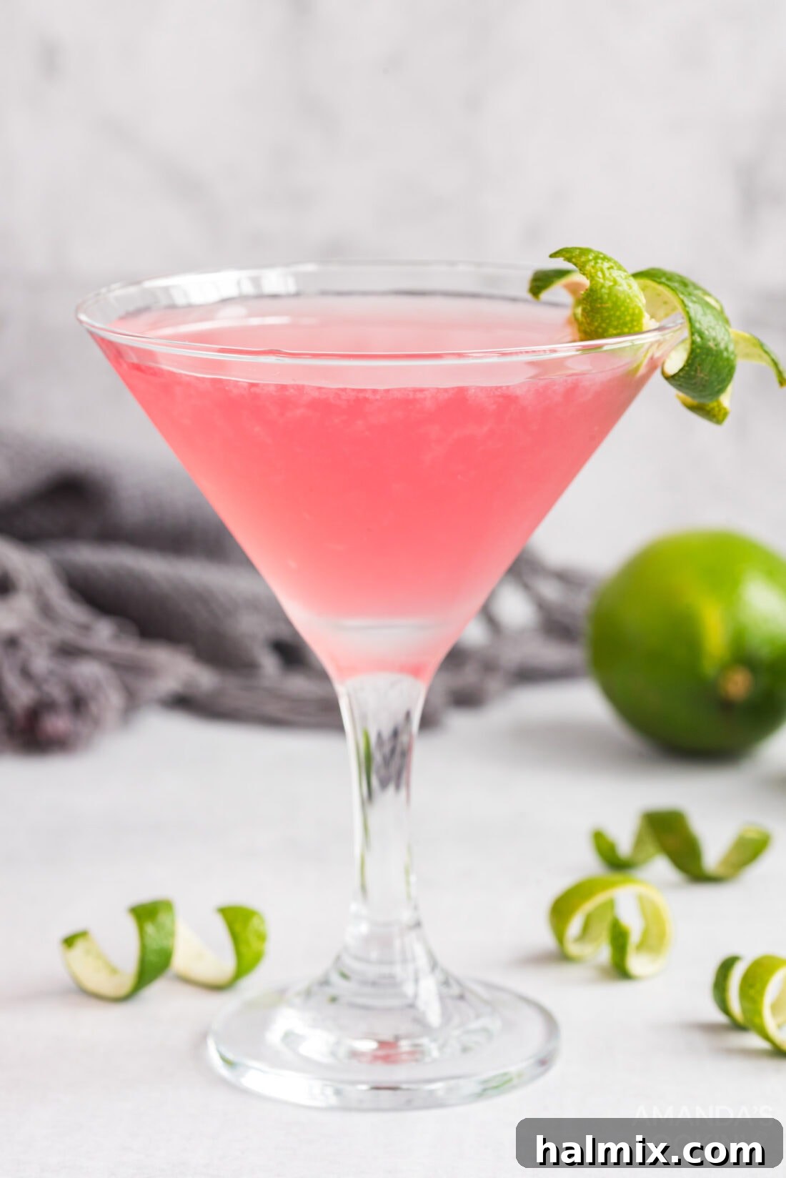 A perfectly made Cosmopolitan cocktail in a martini glass, garnished with a lime wedge, ready to be enjoyed.