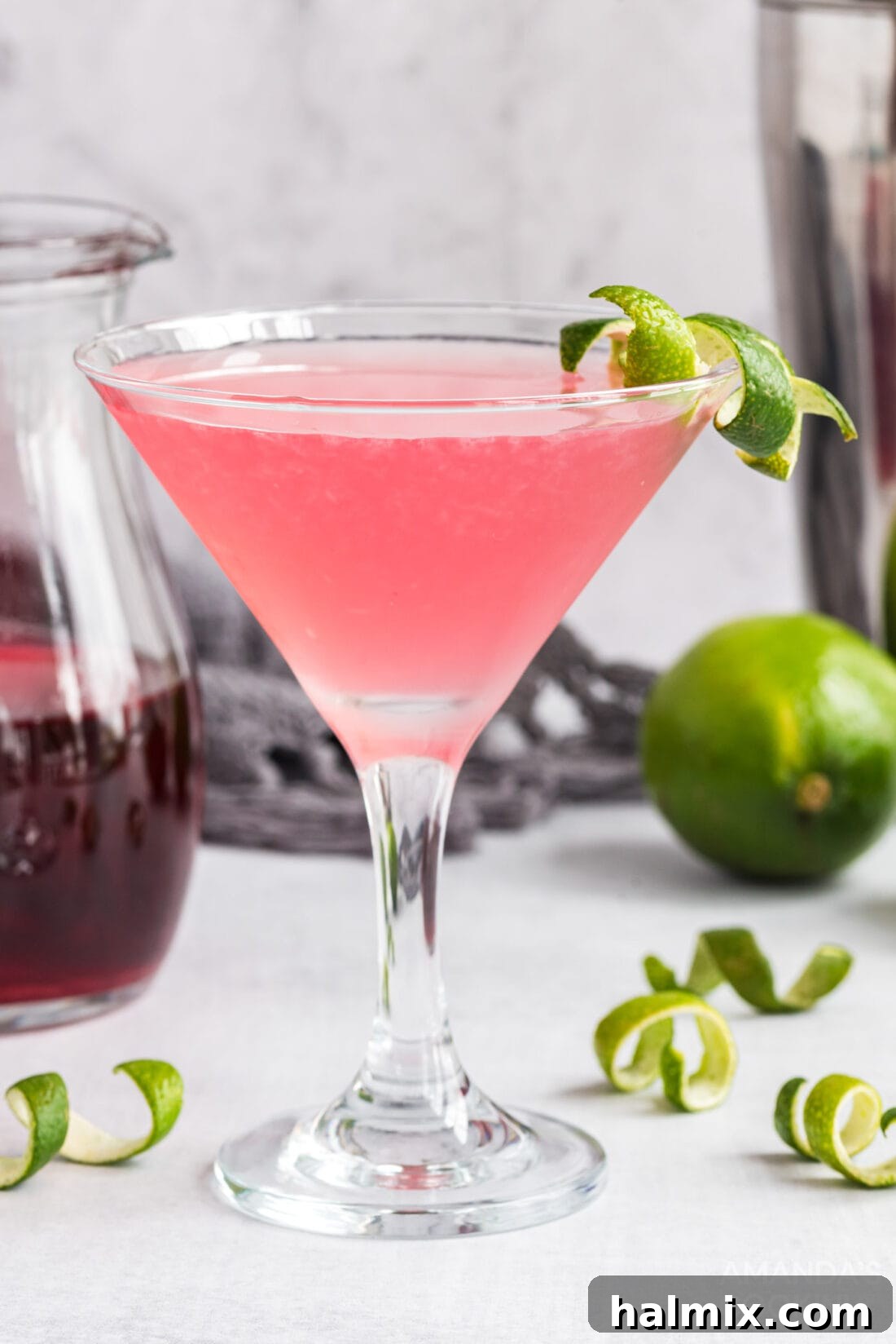 A pristine Cosmopolitan cocktail, artfully garnished with a delicate lime twist, sitting on a bar top ready for enjoyment.