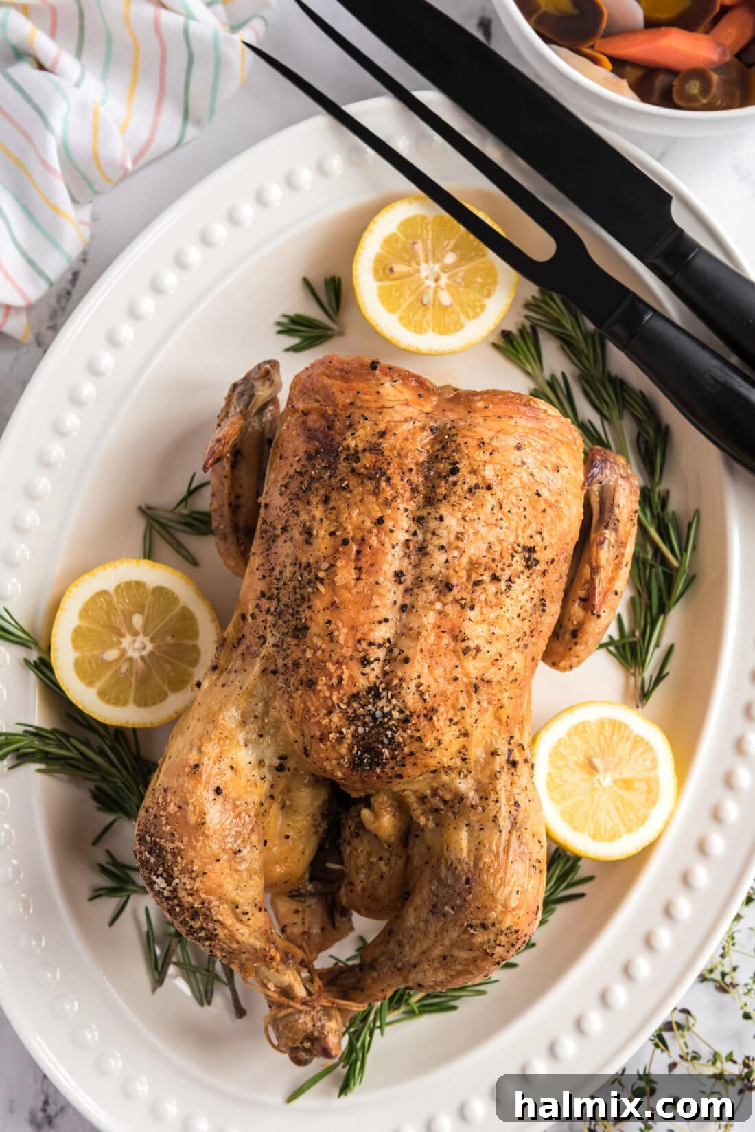 Golden Roasted Chicken 2 A beautifully roasted whole chicken on a pristine white platter, surrounded by carving utensils, showcasing its golden, crispy skin.