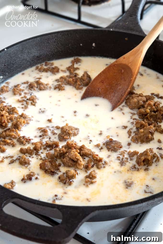Finished creamy sausage gravy simmering in a cast iron skillet, bubbling gently, ready to be served.