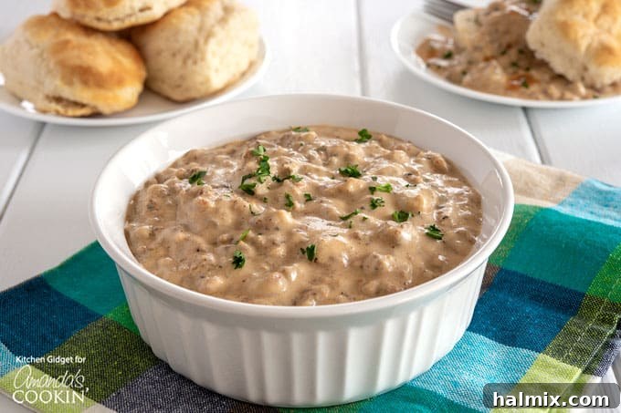 A serving of homemade sausage gravy in a white bowl, garnished with a sprinkle of fresh black pepper, inviting and delicious.