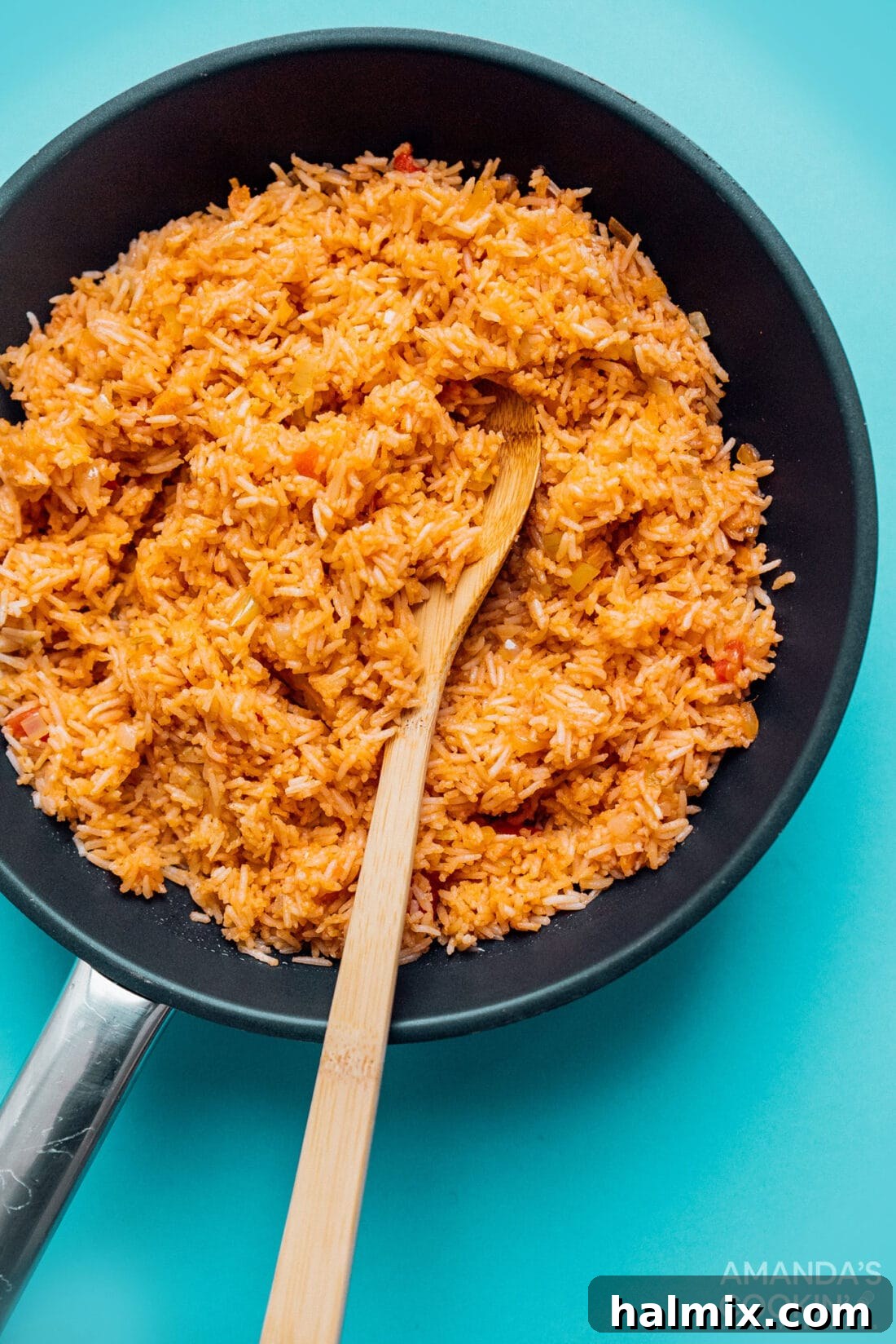 Skillet of freshly cooked Classic Spanish Rice, steaming with aromatic spices and ready to be fluffed and served, showcasing its vibrant color and tender grains.