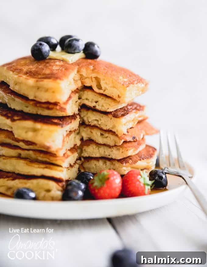 These classic buttermilk pancakes are fluffy, filling, and so delicious. Homemade pancakes are easier than you thought, so throw away that box mix! #breakfast #breakfastrecipes #buttermilkpancakes #pancakes #homemadepancakes Fluffy homemade buttermilk pancakes stacked high with fresh berries and syrup.