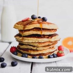 A beautiful plate of stacked buttermilk pancakes adorned with fresh blueberries.