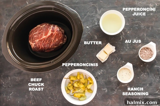 A beautifully arranged flat lay of all the essential ingredients for a Mississippi Pot Roast: a large chuck roast, ranch seasoning packet, au jus mix, two sticks of butter, and a jar of bright green pepperoncini peppers.