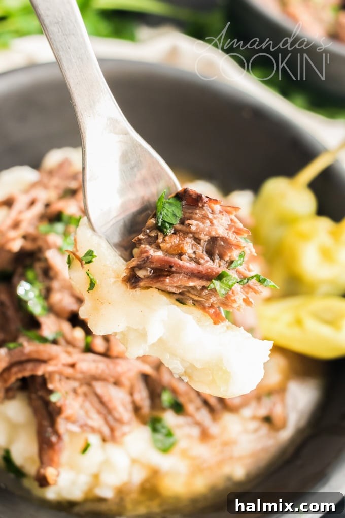 A fork holding a succulent piece of Mississippi Pot Roast, showcasing its perfectly shredded, tender texture and rich, savory juices.