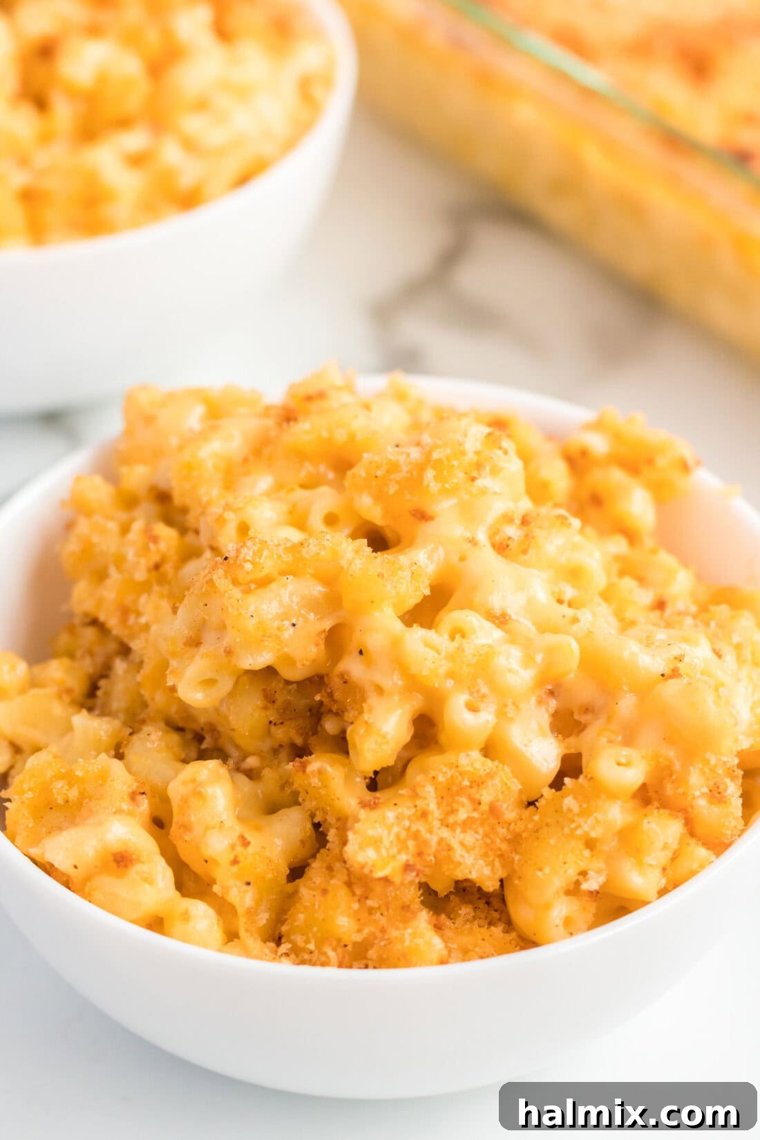Golden-Crusted Macaroni Bake 3 Bowl of creamy baked macaroni and cheese with another bowl in the background, ready to be served.