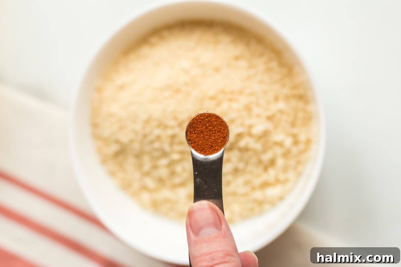 Golden-Crusted Macaroni Bake 9 Paprika being sprinkled into a bowl of panko breadcrumbs for the crispy topping.