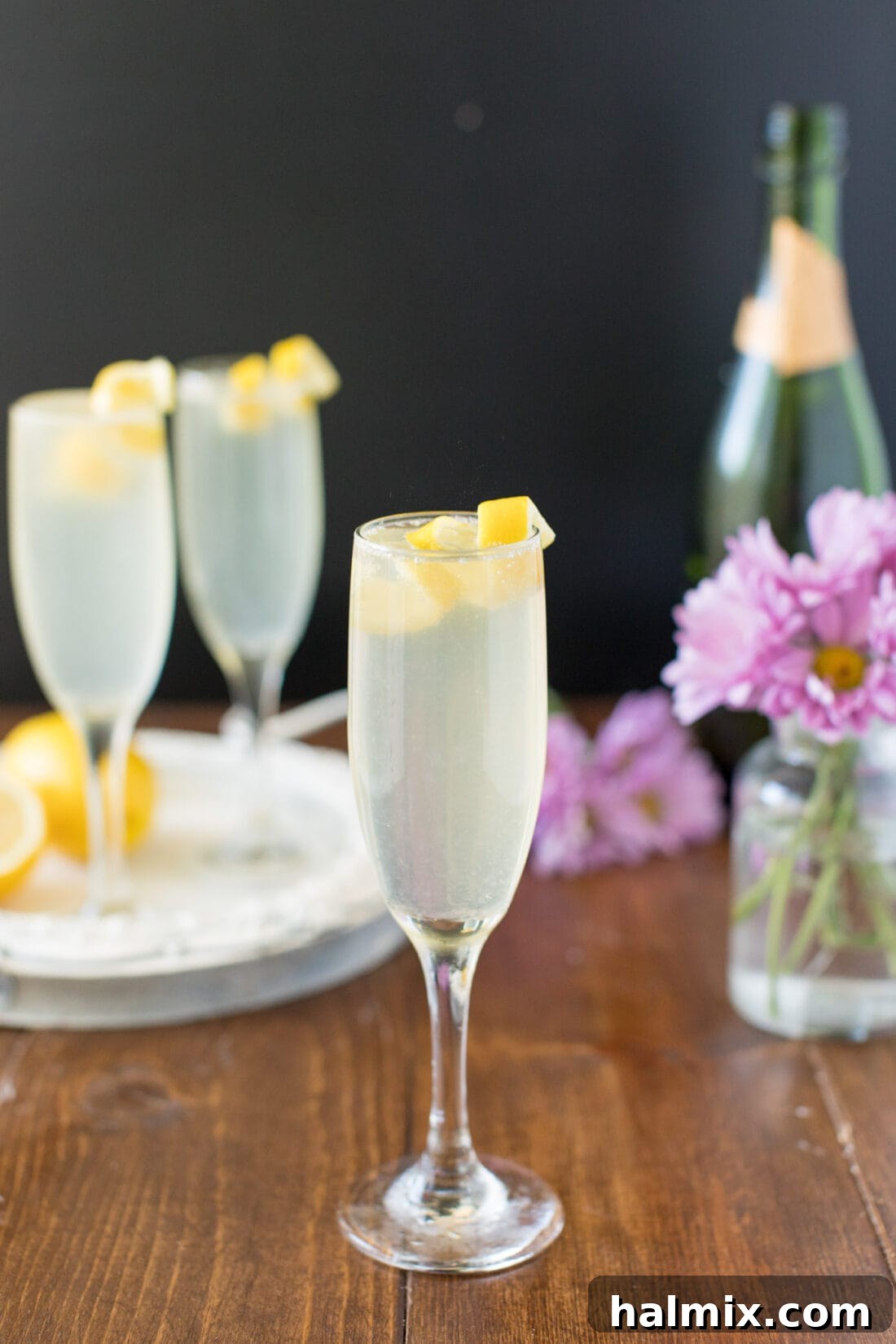 A perfectly prepared French 75 cocktail, garnished with an elegant lemon twist, sparkling in a champagne flute against a soft, inviting background.