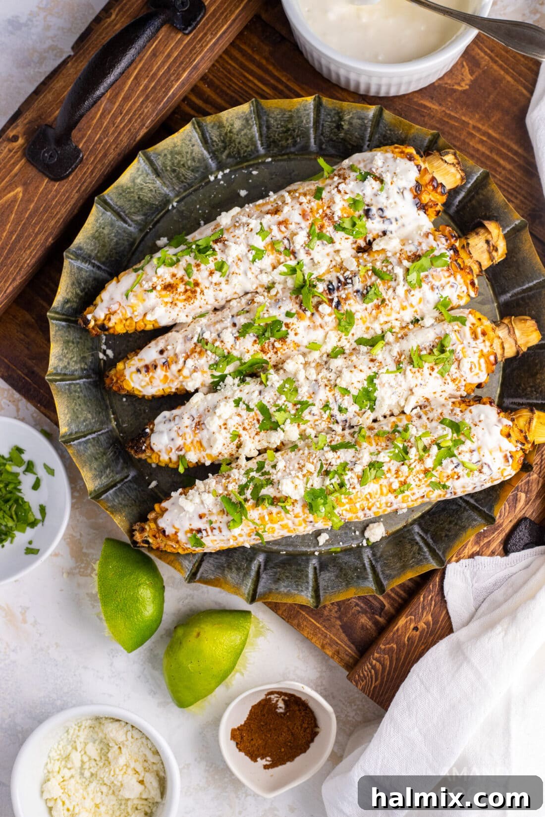 Mexican Street Corn Fiesta 3 Two pieces of Mexican street corn on a white plate, showcasing the creamy coating and cheese.