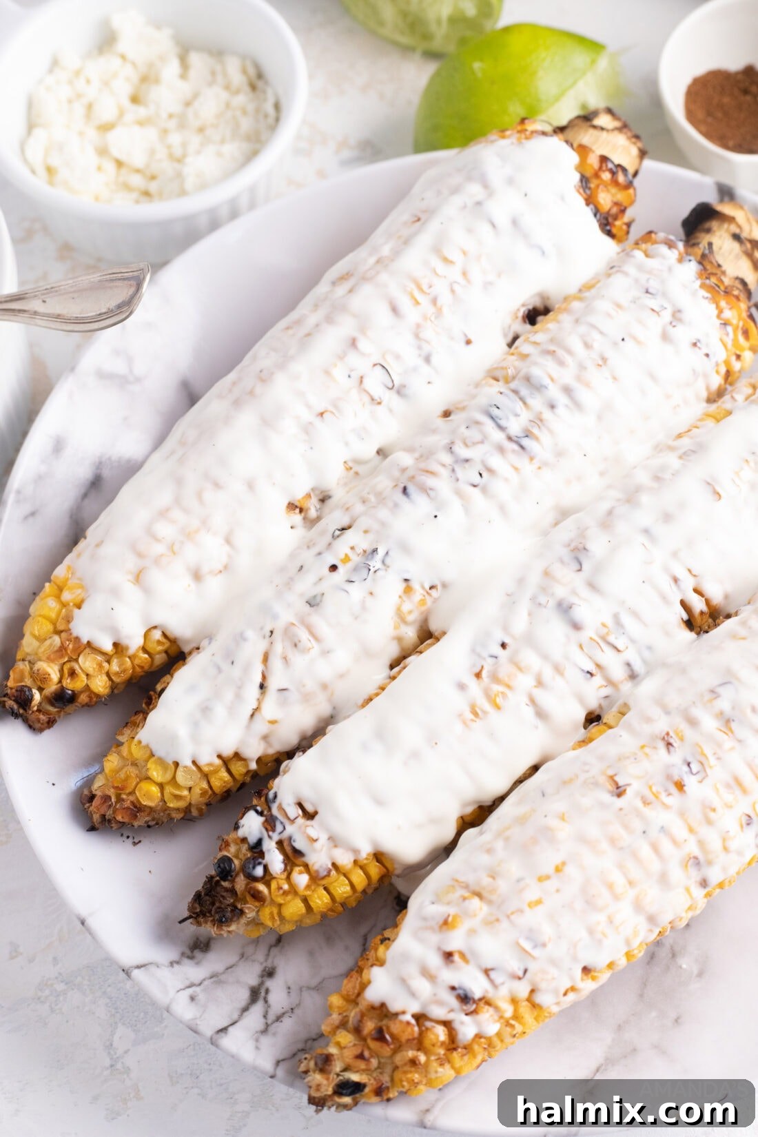 Mexican Street Corn Fiesta 5 Corn cobs being coated with mayonnaise, a crucial step for Elotes.