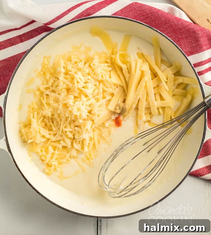 saucepan with a flour roux and shredded cheeses, ready to be melted into a smooth sauce