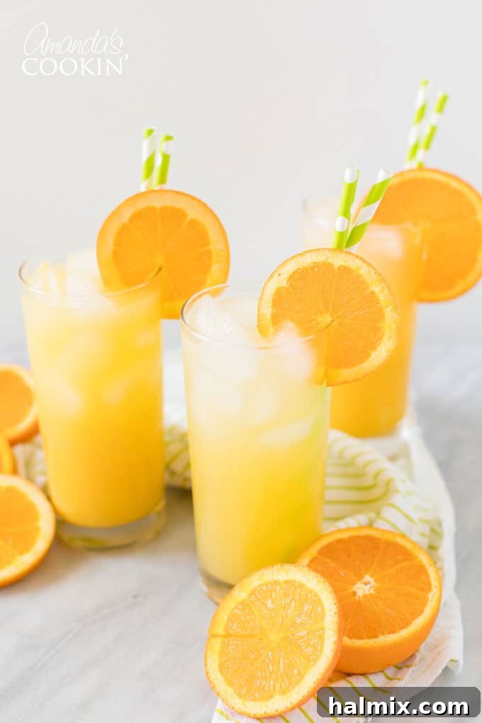Two Screwdriver cocktails in highball glasses, garnished with orange slices and a cocktail pick, set against a bright background.
