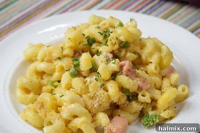 A rich macaroni and cheese casserole with ham and peas, baked to perfection.