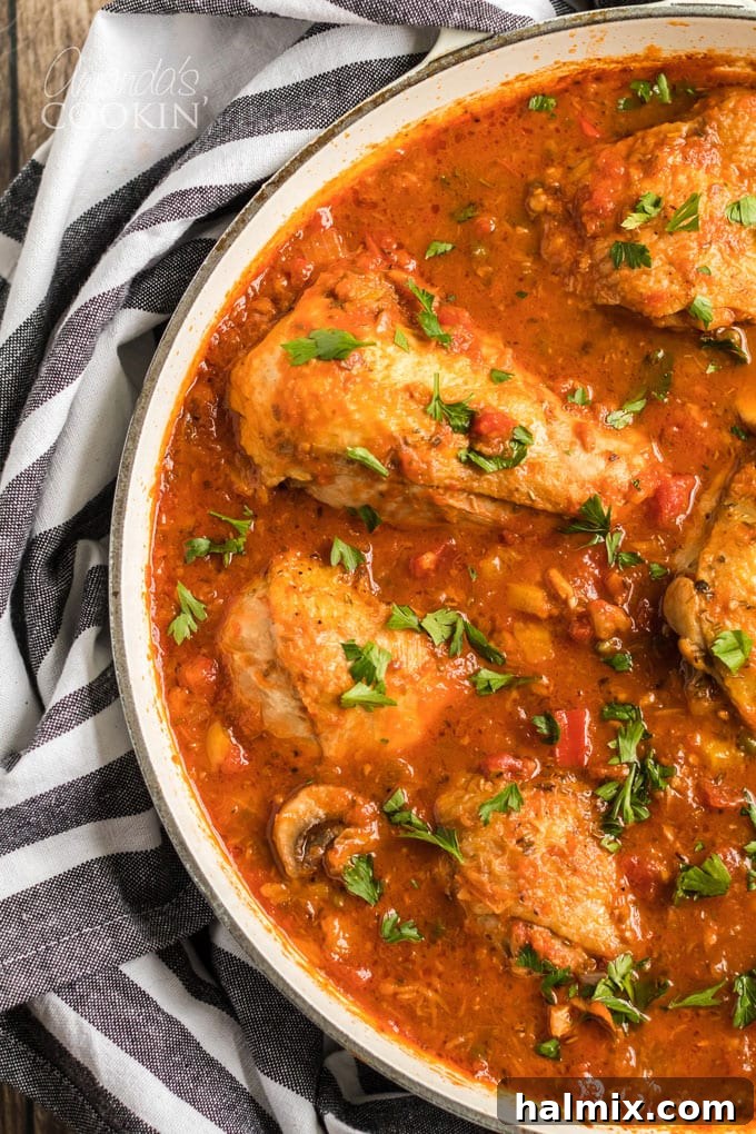 Chicken Cacciatore, a classic stewed chicken recipe with onions, bell peppers, garlic, and capers, slowly cooked on the stovetop. Close-up of Chicken Cacciatore simmering in a pan, highlighting the vibrant vegetables and rich tomato sauce.