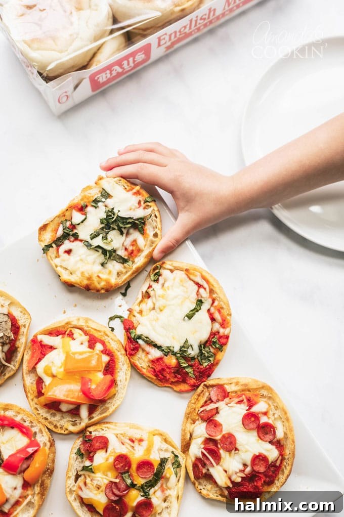 Child's hand reaching for a freshly baked English muffin pizza slice