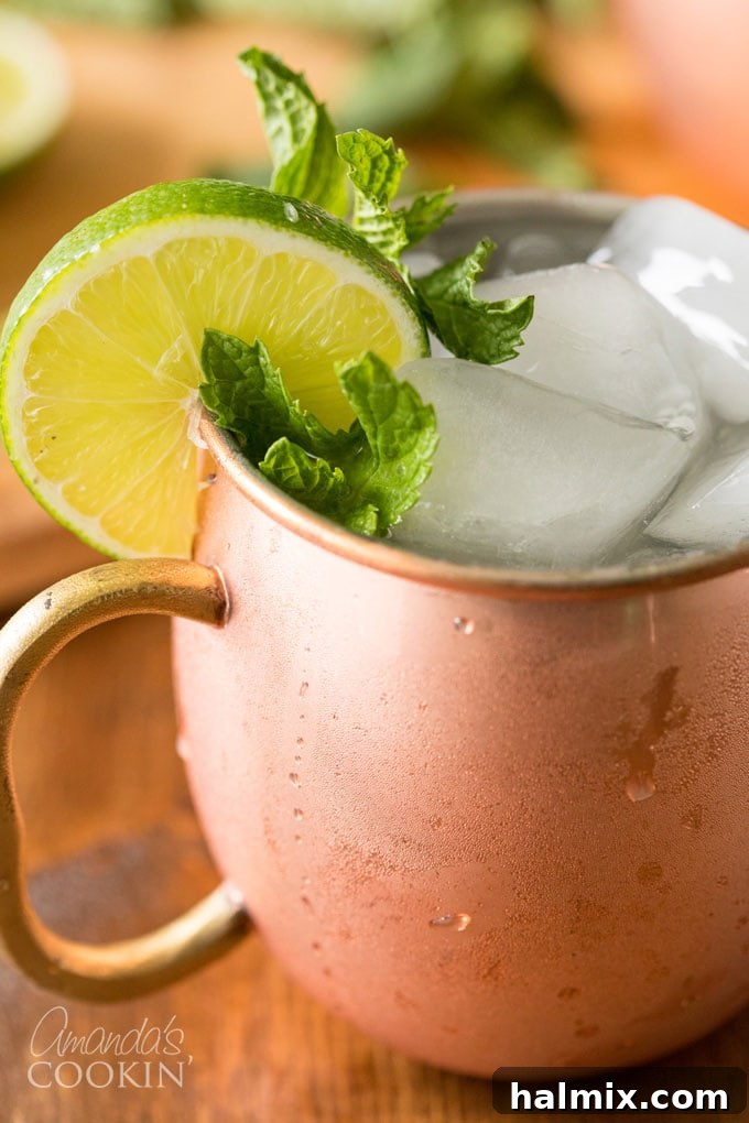 close up photo of moscow mule with lime and mint garnish in copper mug