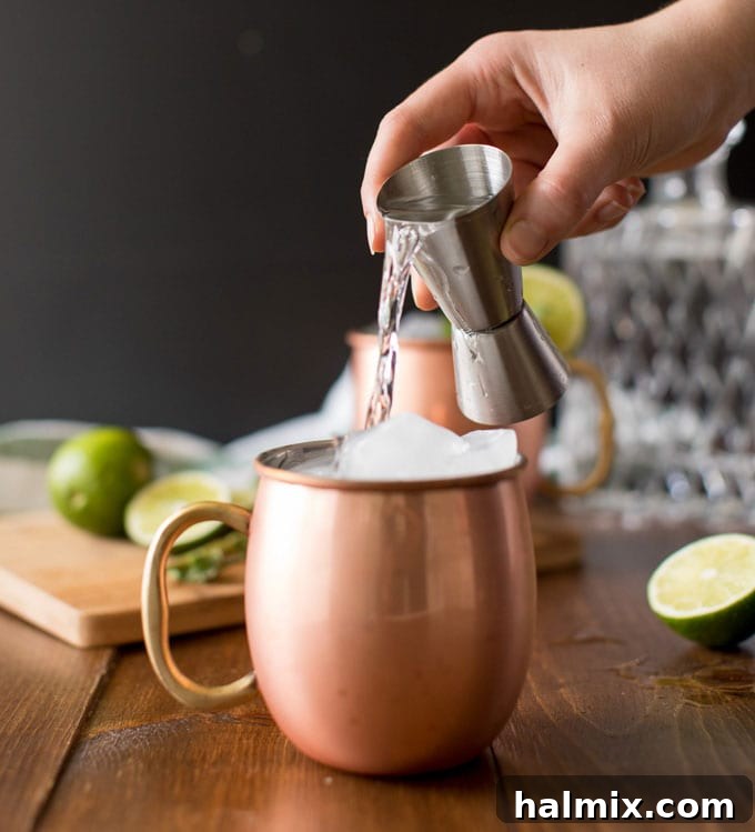 pouring vodka over ice in copper mug