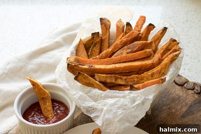 Baked Sweet Potato Fries with a dollop of ketchup on the side, highlighting the golden color and rustic texture of the fries.