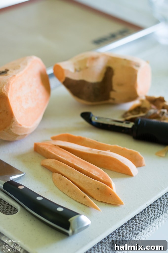 Hands demonstrating the process of peeling and cutting a sweet potato into even, fry-like strips on a wooden cutting board.