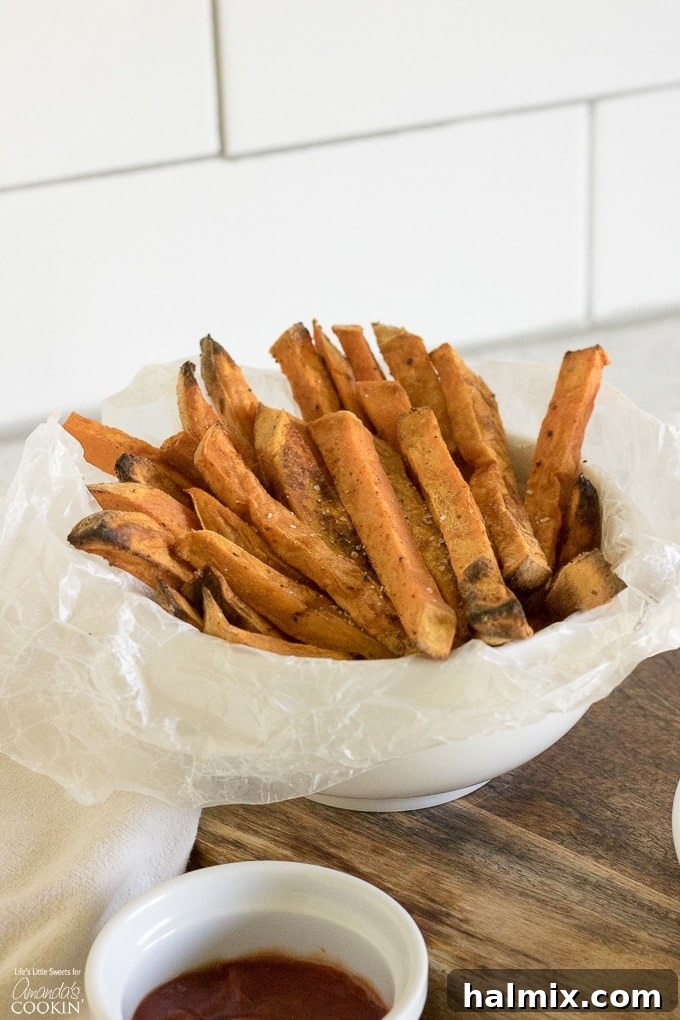 A large bowl overflowing with crispy baked sweet potato fries, seasoned with visible spices, ready to be served.