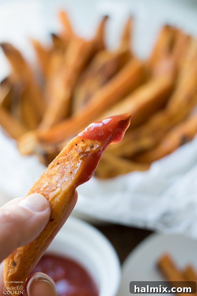Crispy baked sweet potato fries on a plate, with a small dish of ketchup and a fork, ready to be enjoyed.