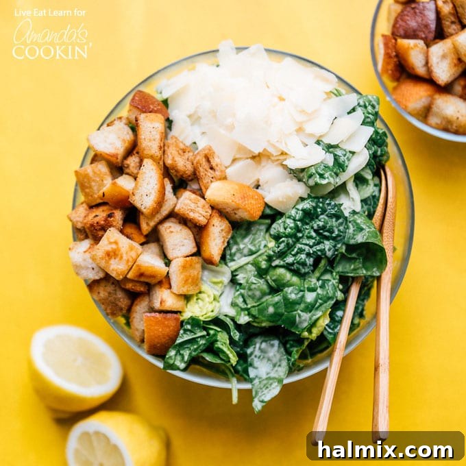 All the fresh ingredients laid out for making Caesar salad, including romaine lettuce, bread, parmesan cheese, and dressing components