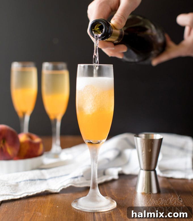 Slowly pouring sparkling Prosecco into a champagne flute already containing peach puree, creating a beautiful Bellini.