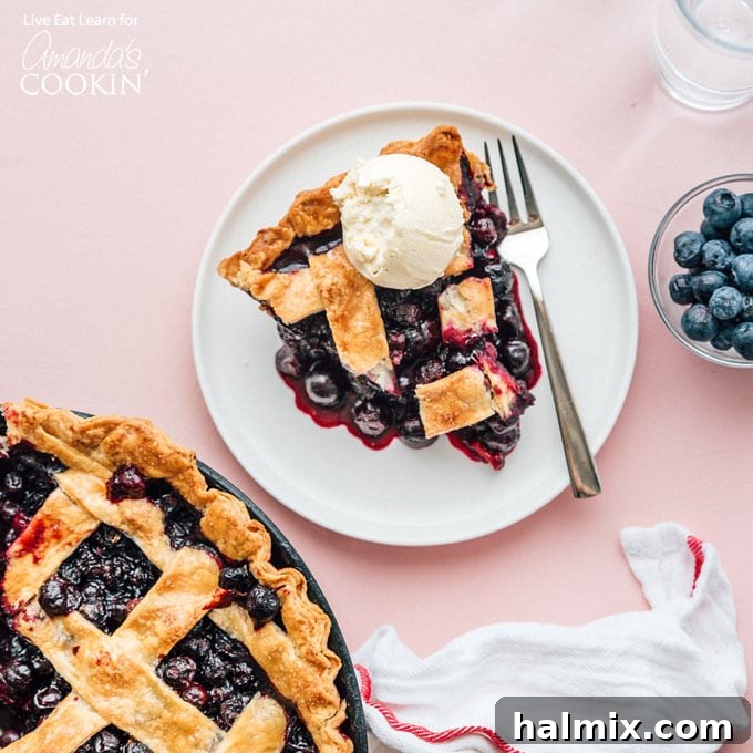 A whole homemade blueberry pie, freshly baked with a golden-brown lattice crust, resting on a rustic wooden table, ready to be served.