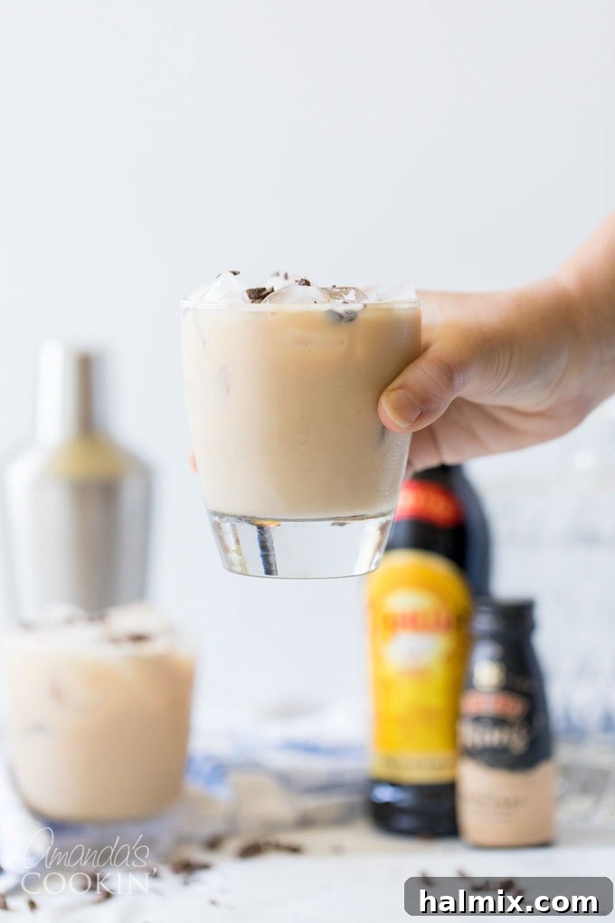 Flowing Devastation 6 Hand lifting a glass of Mudslide cocktail garnished with chocolate shavings