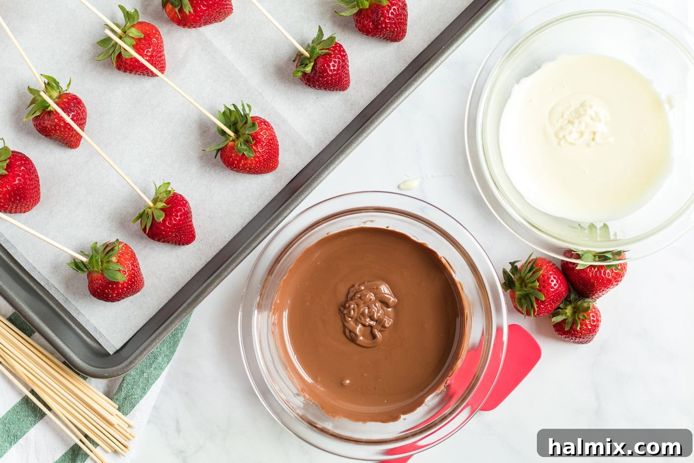 strawberries skewered on a pan and a bowl of melted chocolate